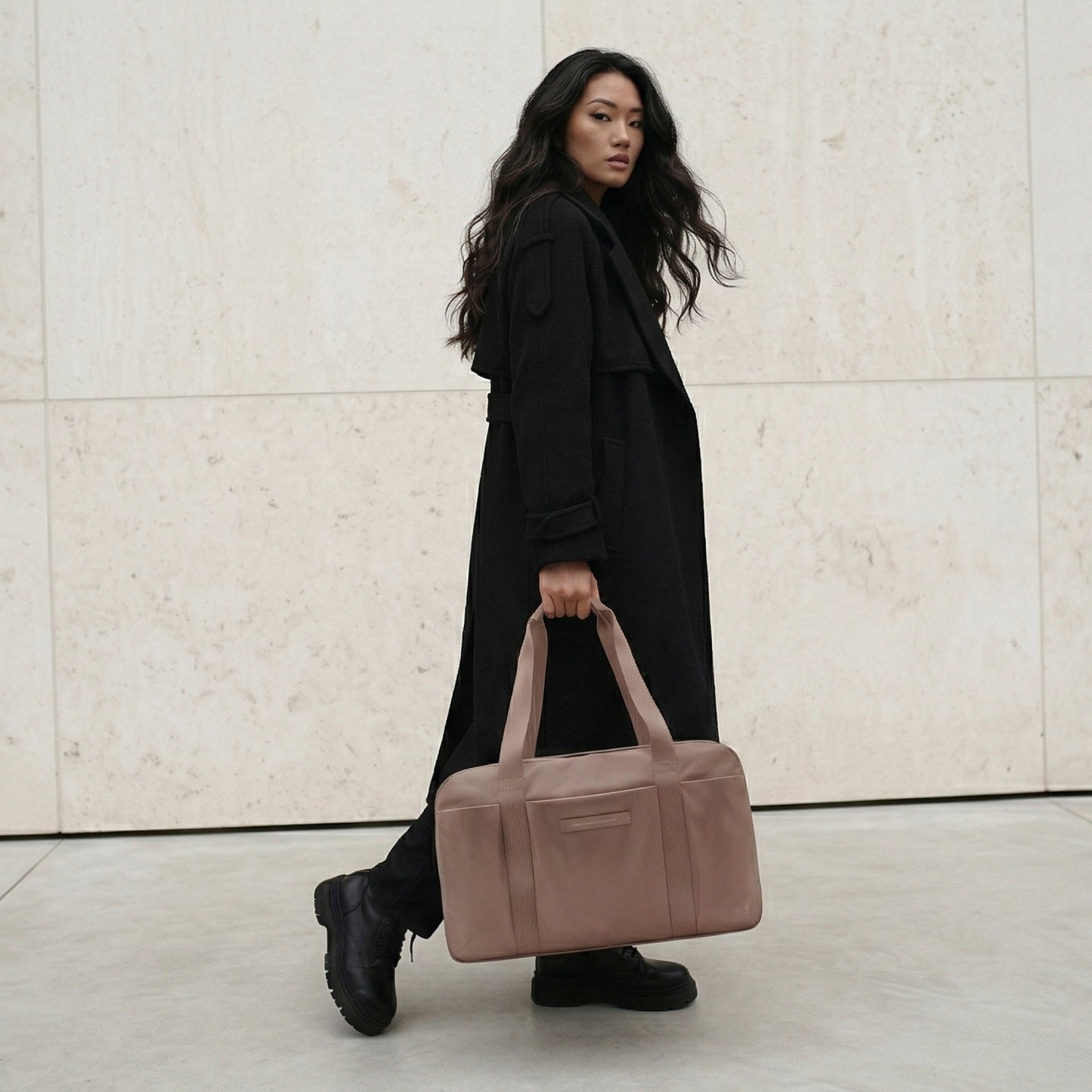 Woman holding a brown bag against a light-colored wall